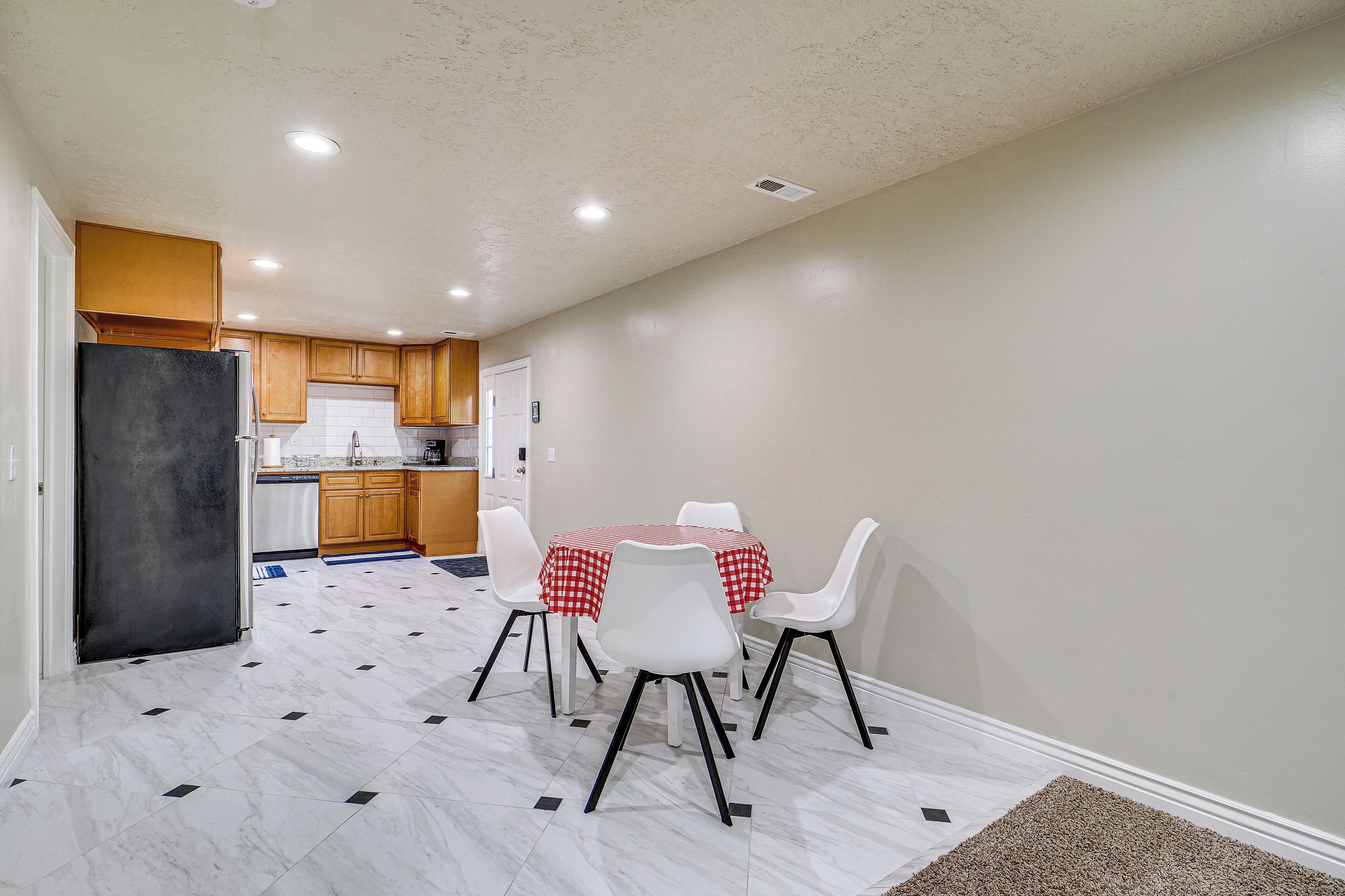 A compact kitchen with wooden cabinets, a black refrigerator, and a dining area with a table and chairs.