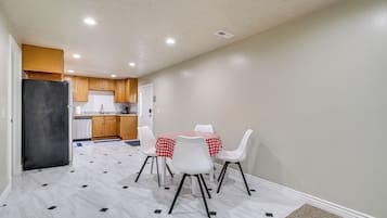 A compact kitchen with wooden cabinets, a black refrigerator, and a dining area with a table and chairs.