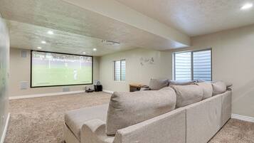 A home theater room with a large screen, a sectional sofa, and a carpeted floor.