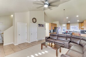 A spacious living room with a large leather sectional sofa, a wooden coffee table, and a ceiling fan.