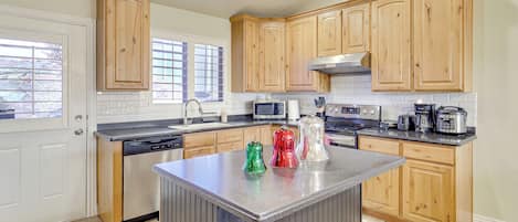 A kitchen with wooden cabinets, a central island, a dishwasher, a microwave, and a stove.