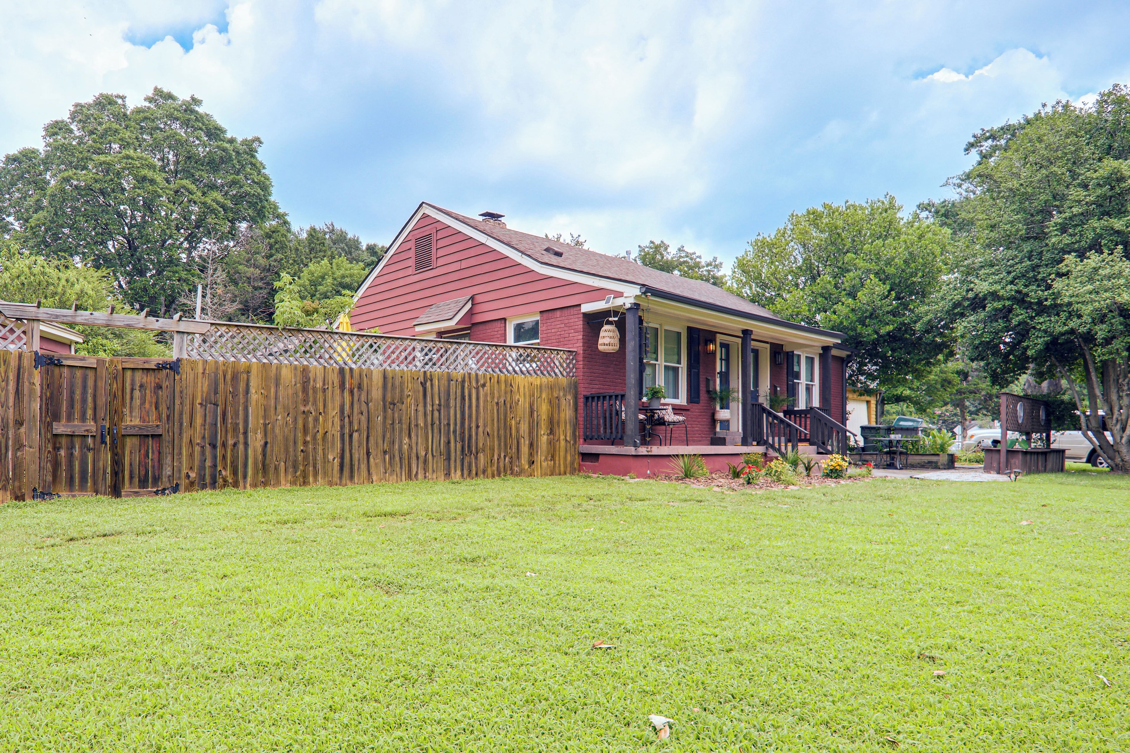 A red house with a wooden fence and a grassy yard.