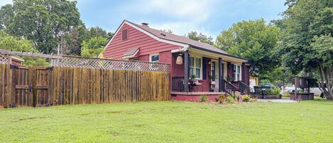A red house with a wooden fence and a grassy yard.