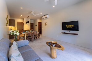 Un salon moderne avec un canapé, une table basse et un téléviseur à écran plat fixé au mur.