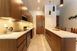 Une cuisine moderne avec des meubles en bois, des appareils électroménagers en acier inoxydable et des luminaires suspendus.