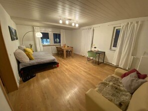 Ein gemütlicher Raum mit Bett, Tisch, Stuhl und einer Sitzecke.