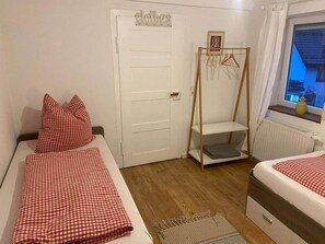 Ein Schlafzimmer mit zwei Betten, einem Kleiderschrank, einem Hängebrett und einem Fenster mit Blick.