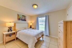 A hotel room with a bed, two bedside tables with lamps, a painting on the wall, a window with curtains, and a wooden dresser. - 6 Mi to Dtwn! Centrally Located Sarasota Home (Sarasota)