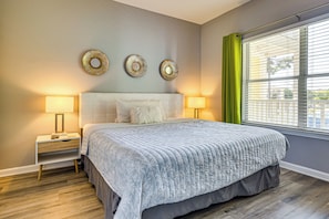 A bedroom with a bed, two bedside tables, a window with blinds, and wall decor. - Near Grand Boulevard & Beaches! Coastal Condo (Miramar Beach)