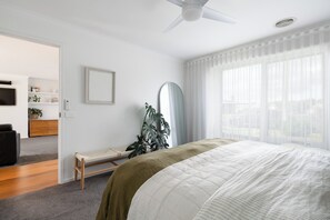 Ein Schlafzimmer mit einem Bett, einer Bank, einem Spiegel und einer Pflanze.