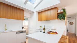 Een moderne keuken met een centraal eiland, houten kastjes en een dakraam.