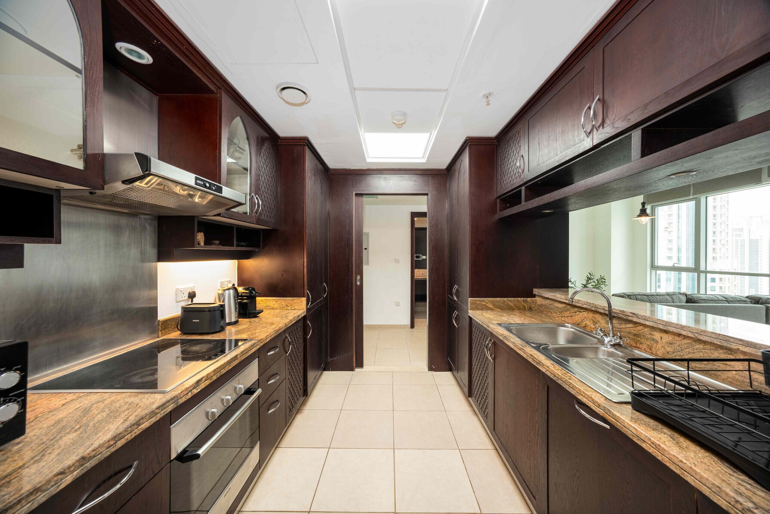 Una cocina moderna con armarios de madera oscura, electrodomésticos de acero inoxidable y un ventanal con vistas a la ciudad.