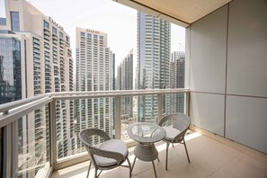 A balcony with two wicker chairs and a glass table, overlooking a cityscape with high-rise buildings. - Cozy 1BR | Steps from Burj Khalifa & Mall (Dubai)