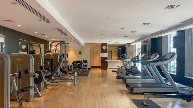 Ett gym med konditionsmaskiner, styrketräningsstationer och en spegel.