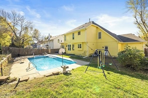 Quintal residencial com piscina, balanço e casa.