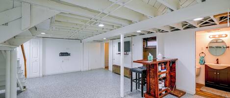 A room with a high ceiling, exposed beams, a white door, a small table with a mirror, and a radiator.