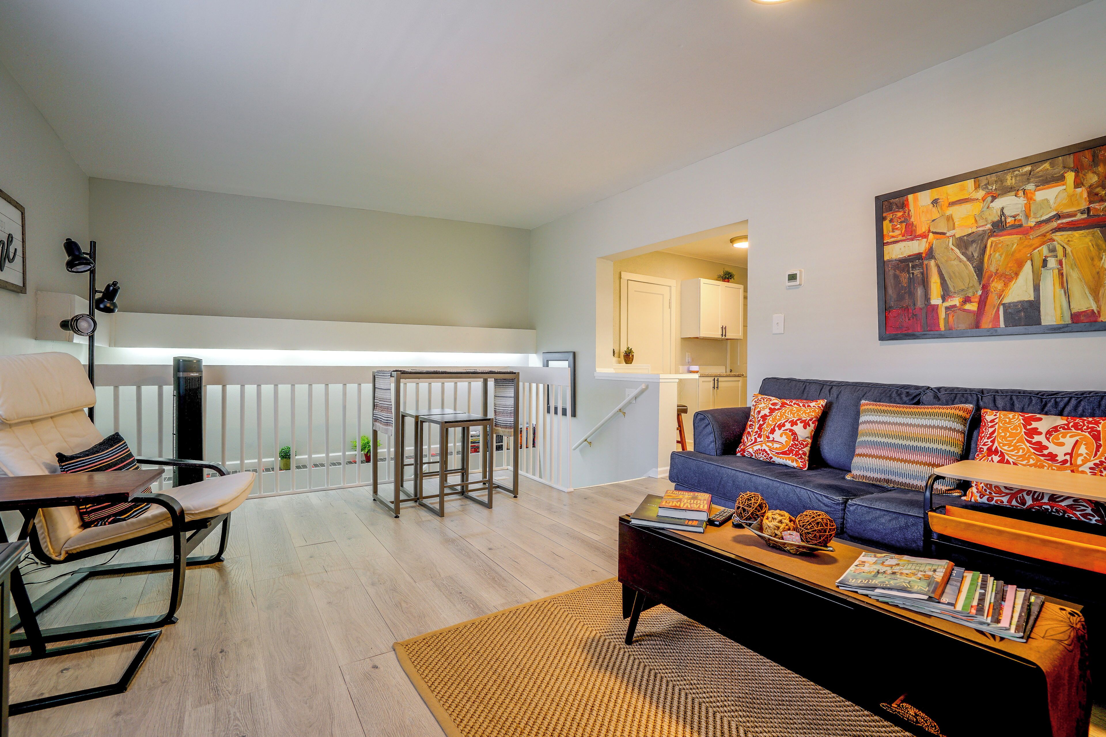 A modern living room with a sofa, coffee table, and a painting on the wall.