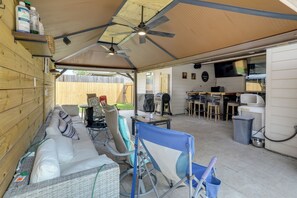 A covered patio area with a ceiling fan, outdoor seating, and a barbecue grill.