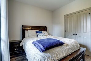 Un dormitorio con cama, mesita de noche, cómoda y armario.
