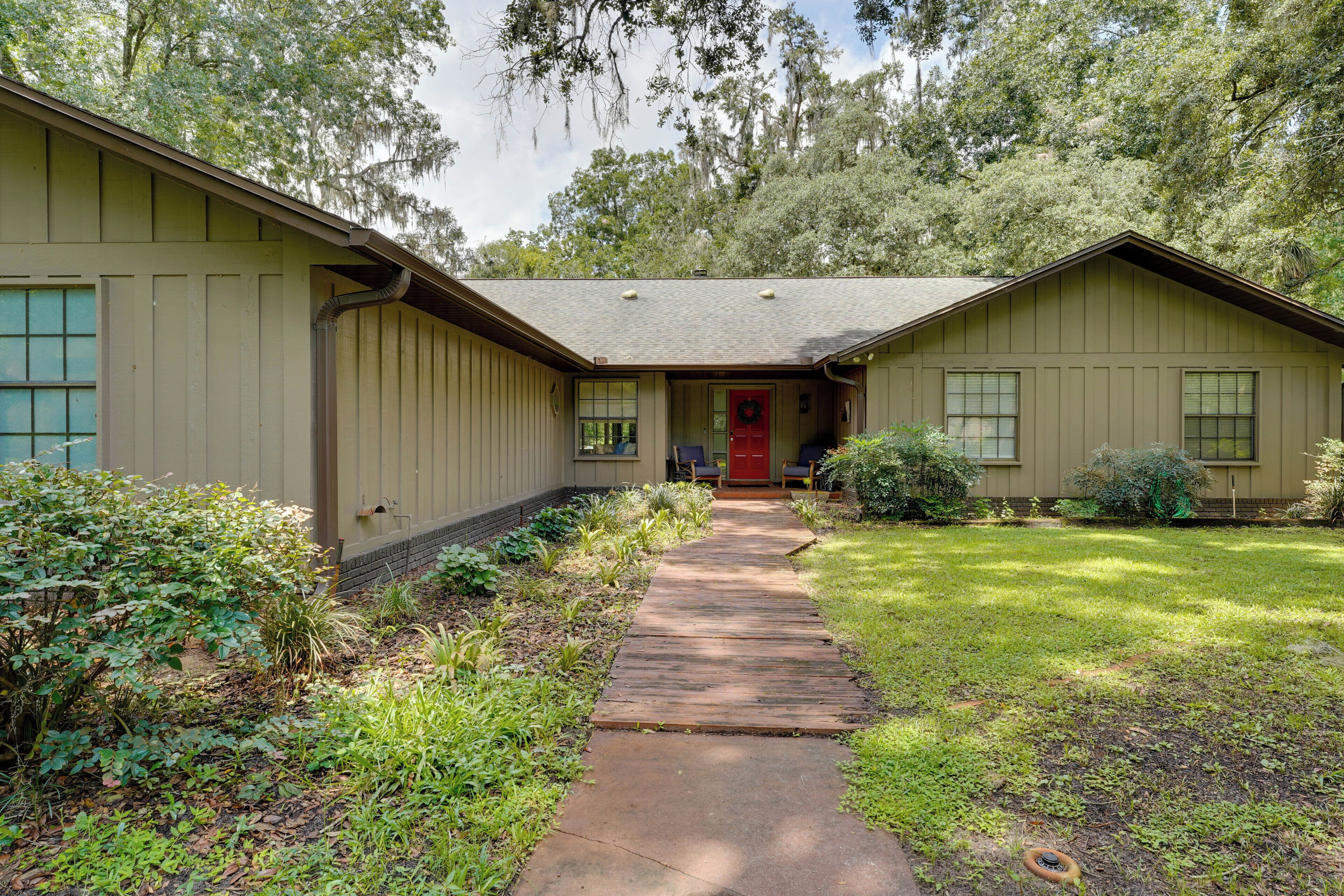 A two-story house with a front porch, a red door, and a pathway leading to the entrance.