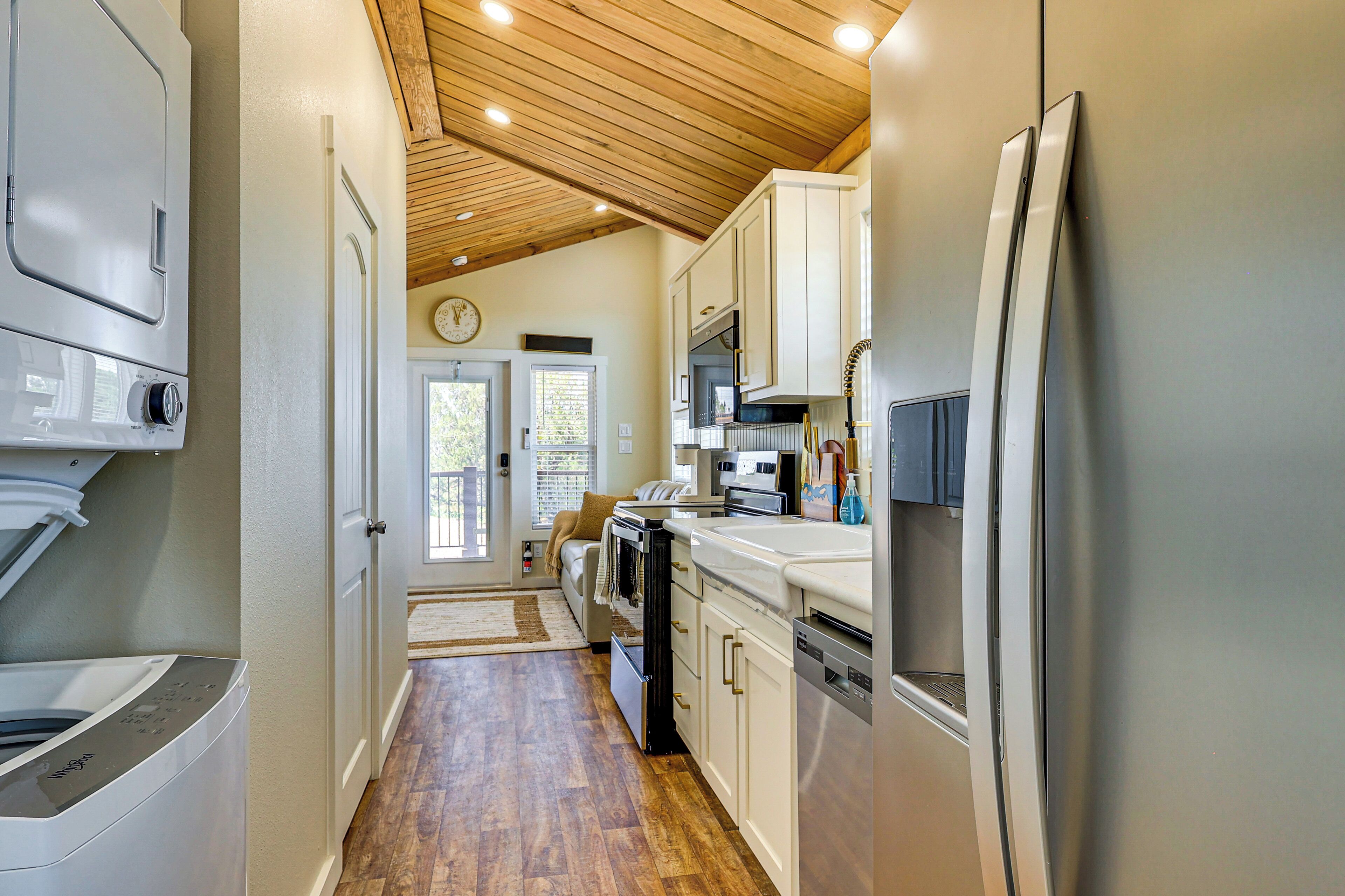 A kitchen with wooden flooring, white cabinets, a stainless steel refrigerator, and a microwave.