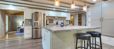 A spacious kitchen with a large island, stainless steel appliances, and pendant lighting.