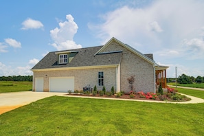 A two-story house with a garage, a covered porch, and a landscaped front yard.