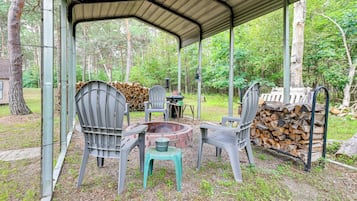 An outdoor covered seating area with chairs and a fire pit.