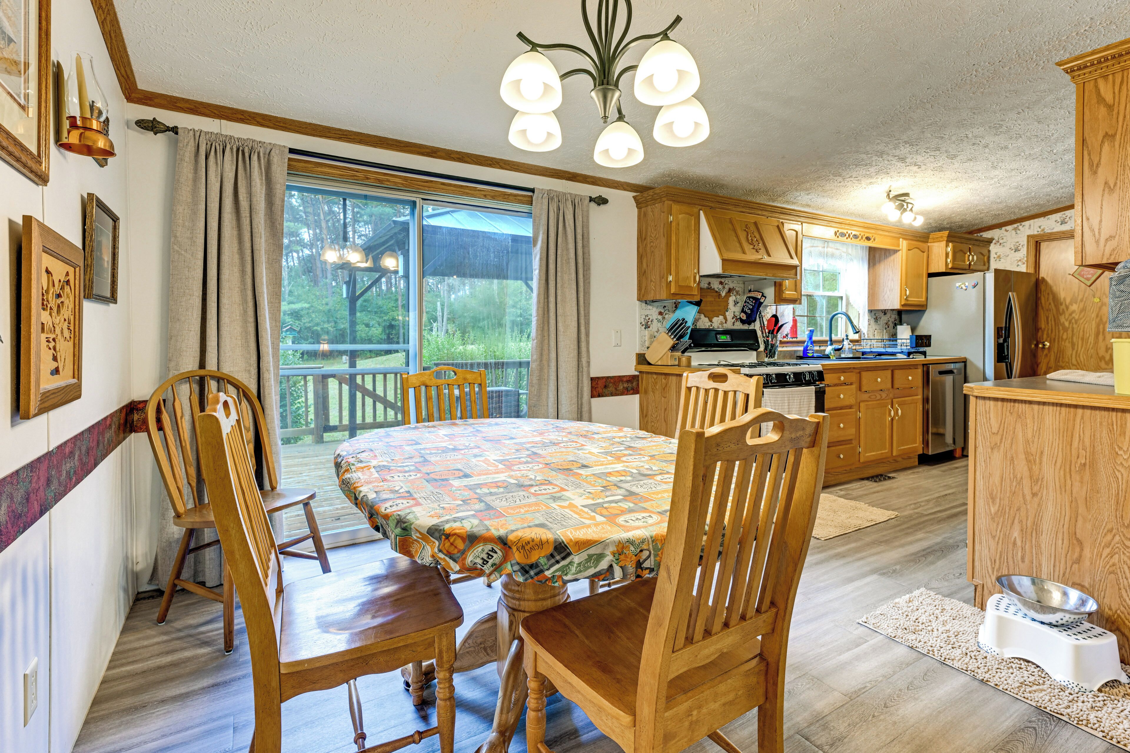 A dining area with a table set for four, wooden chairs, and a view of the outdoors through a large window.