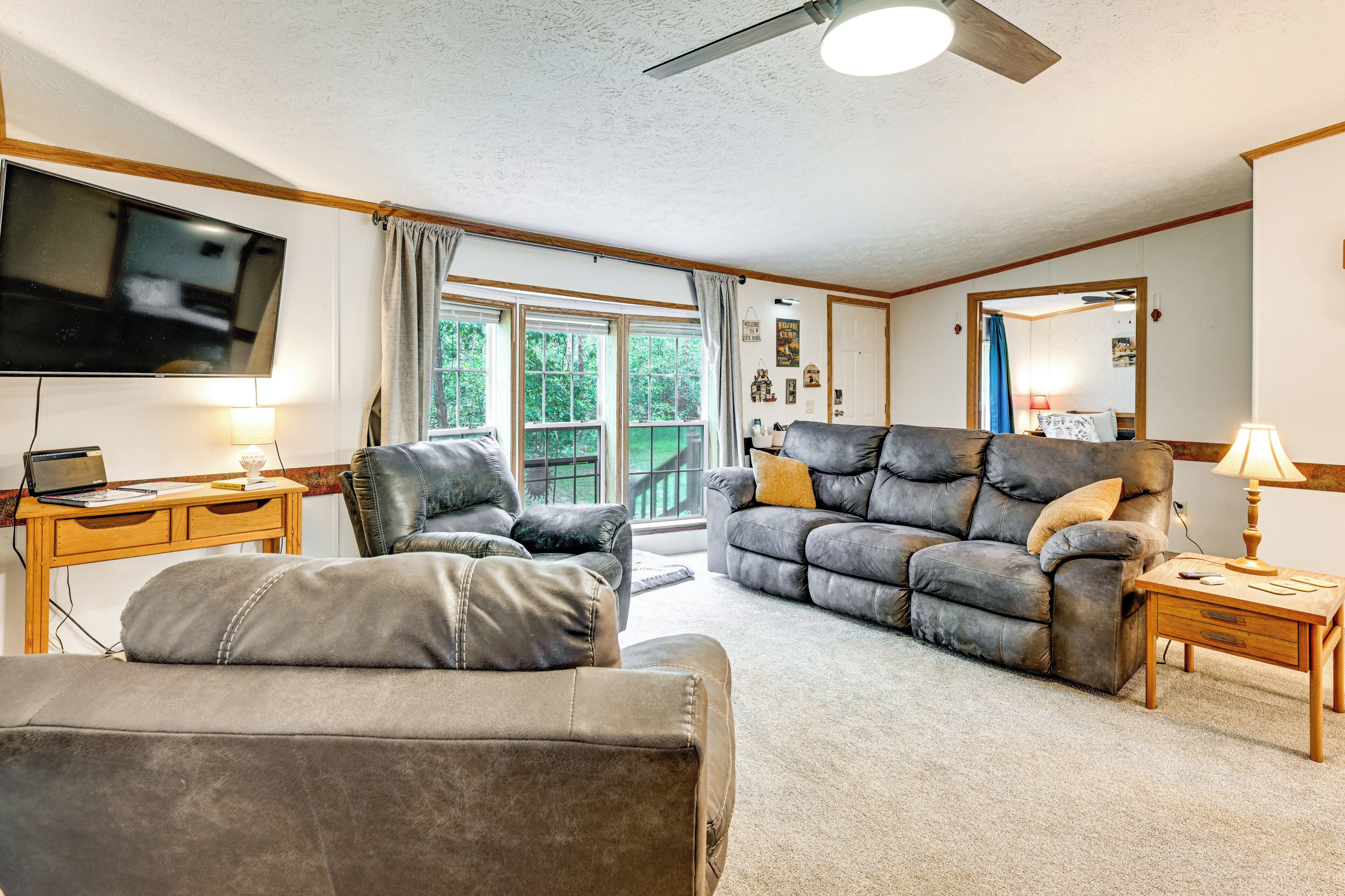 A living room with a leather sofa, a wooden desk, a flat-screen TV, and a ceiling fan.