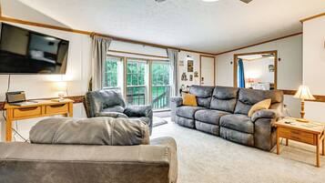 A living room with a leather sofa, a wooden desk, a flat-screen TV, and a ceiling fan.
