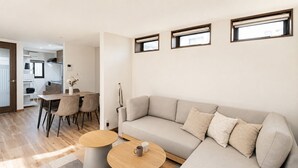 A modern living room with a sofa, two round tables, a dining area with chairs, and a kitchen in the background. - AYA - Self Check-In Only (Osaka, Chuo Ward)