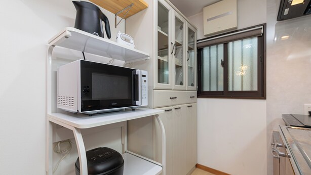A compact kitchen with a microwave on a white shelf, a kettle, and a rice cooker below. - AYA - Self Check-In Only (Osaka, Chuo Ward)
