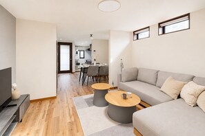 A modern living room with a grey sofa, two round coffee tables, and a TV on a stand. - AYA - Self Check-In Only (Osaka, Chuo Ward)