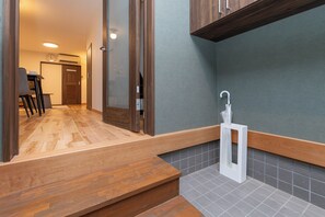 A modern bathroom with a wooden vanity, a towel dispenser, and a tiled backsplash. - AYA - Self Check-In Only (Osaka, Chuo Ward)