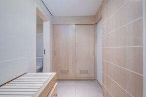 A narrow hallway with a wooden wardrobe, a bed with a wooden frame, and a white tiled floor. - Great ap With Pool in Resort in Jurere Jbv157 (Florianópolis)