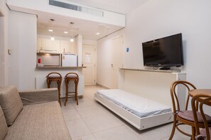 A compact living space with a kitchenette, a sofa, a single bed, and a TV. - Great ap With Pool in Resort in Jurere Jbv157 (Florianópolis)