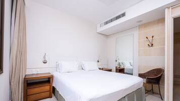 A hotel room with a large bed, bedside tables, a chair, a mirror, and a wardrobe.