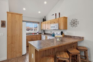 Una cocina con armarios de madera, microondas y encimera de granito.