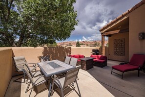 Une terrasse extérieure avec une table et des chaises, un barbecue et une vue sur le paysage désertique.