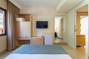 Ett hotellrum med en säng, en TV, en garderob, ett skrivbord och en spegel.