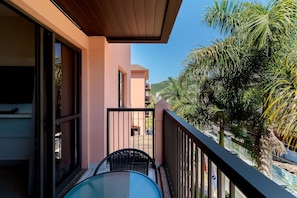 Un balcon avec une table et des chaises, une vue sur un immeuble et des palmiers.