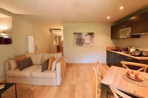 A living room with a sofa, a dining table with chairs, a kitchen area with cabinets and a microwave, and a framed picture on the wall. - Suite 2 at Maison Madamicella / heated pool (Corse-du-Sud)