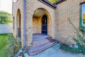 A brick house with a front porch, a black door, and a small garden area. - Clover Cottage - 1 mile to ND - Cozy Getaway (South Bend)