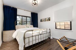 A bedroom with a bed, a radiator, a window with curtains, and a wall-mounted picture. - Clover Cottage - 1 mile to ND - Cozy Getaway (South Bend)