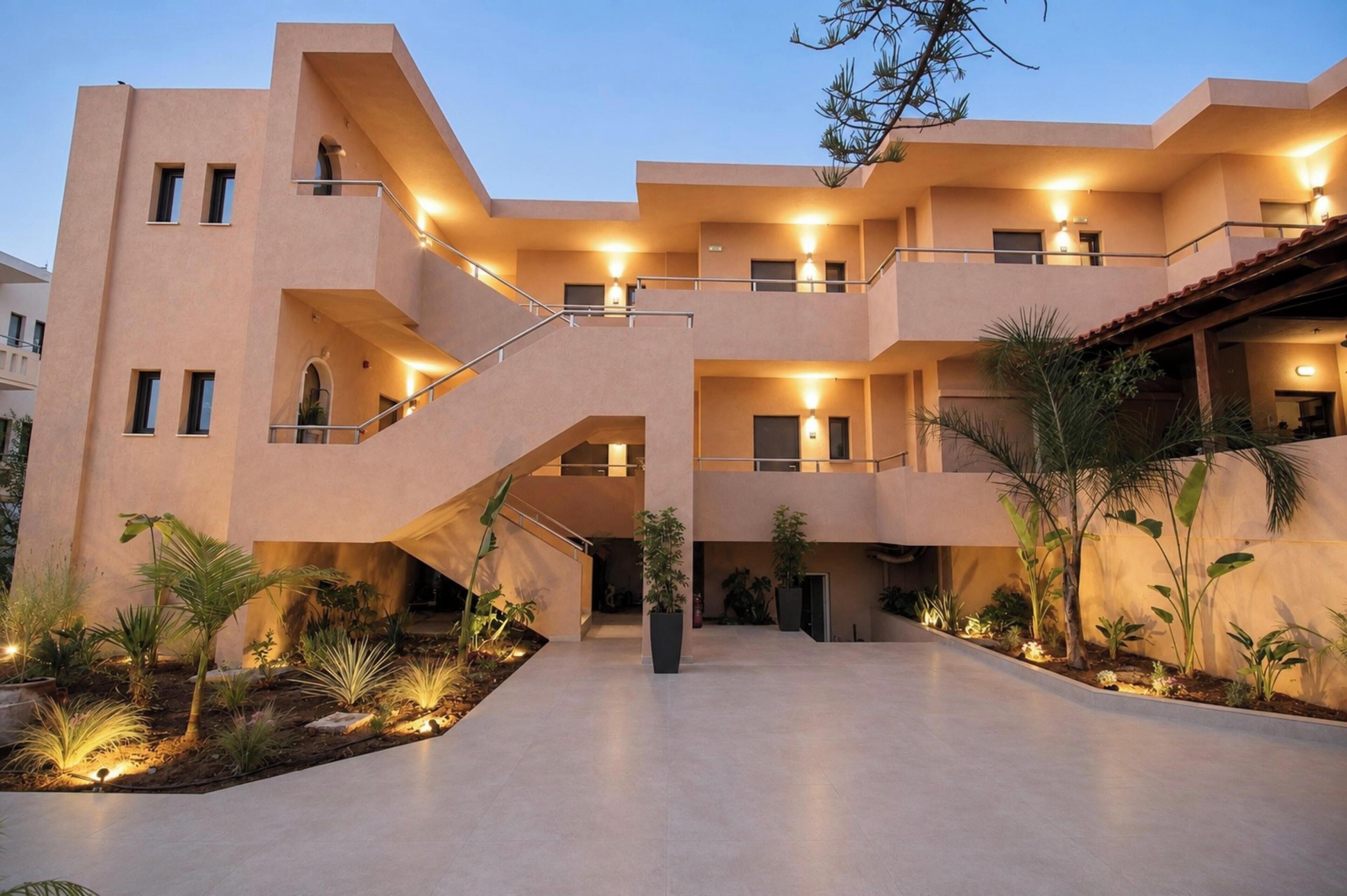 A multi-story hotel with a central courtyard, outdoor lighting, and a variety of plants.