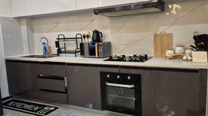 A modern kitchen with a built-in oven, a microwave, and a gas stove. - Luxury Two bedroom Apartment  in  kileleshwa (Nairobi)