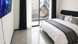 Une chambre moderne avec un lit, un fauteuil suspendu et un téléviseur fixé au mur.
