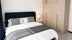A hotel room with a bed, a nightstand, a lamp, and a wardrobe. - Luxury Two bedroom Apartment  in  kileleshwa (Nairobi)