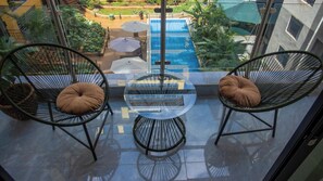 A balcony with two chairs and a small table, overlooking a swimming pool and greenery. - Luxury Two bedroom Apartment  in  kileleshwa (Nairobi)